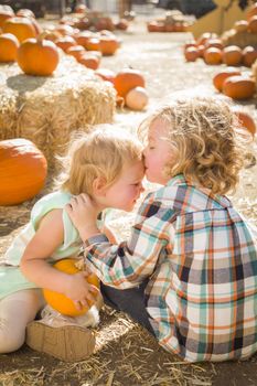 Sweet Little Boy Kisses His Baby Sister in a Rustic Ranch Setting at the Pumpkin Patch.
