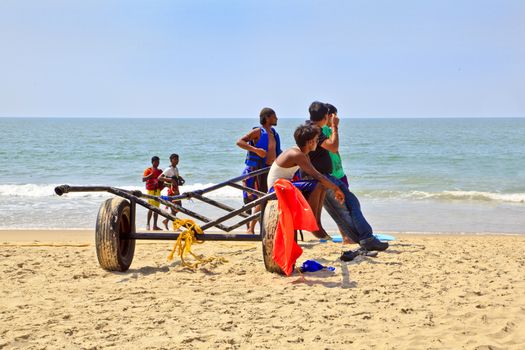 Horizontal Beach tropical landscape of para gliding sales assistants sat on a trailer waiting for the next fare under the mid day Indian sun. Shot location Uttorda Beach, Goa, India