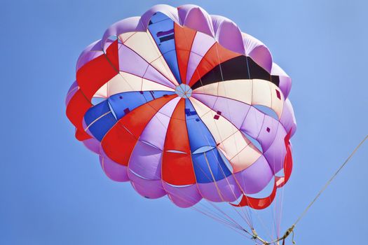 Horizontal landscape of abstract para gliders parachute from a view point directly below against a rich blue sky. Generic shot location was Uttorda Beach, Goa, India