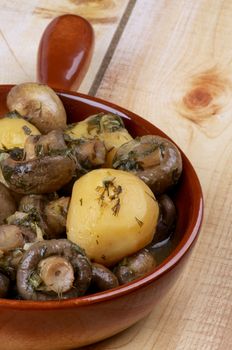 Delicious Stew with Champignon Mushrooms, Roasted Potato, Dill, Parsley, Leek and Onion in Brown Frying Pan closeup on Wooden background