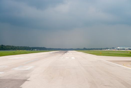 Wide airport runway under dark cloudy storm sky