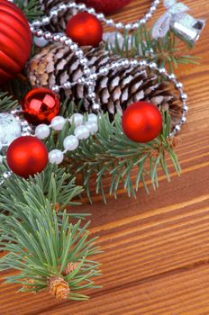 Frame of Spruce Branch and Fir Cones with Red and Silver Baubles, Bows, Pearl and Silver Beads closeup on Wooden background