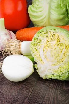 Raw Fresh Vegetable Set with Onion, Garlic, Leek, Carrot, Tomato and Cabbage closeup on Dark Wooden background