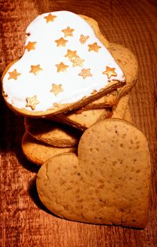 Stack of Delicious Christmas Gingerbread Hearts with Icing and Golden Shape Stars closeup on wooden background