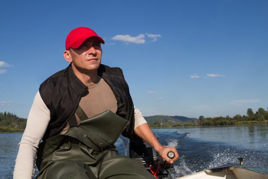 man steers the boat with outboard motor