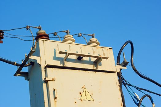Old transformer with insulators and wires on a background azure sky