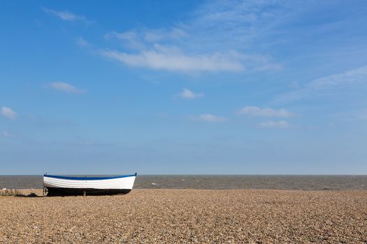 Ancient wooden painted fishing boat on pebble beach by North Sea in Aldeburgh Suffolk on East coast of England