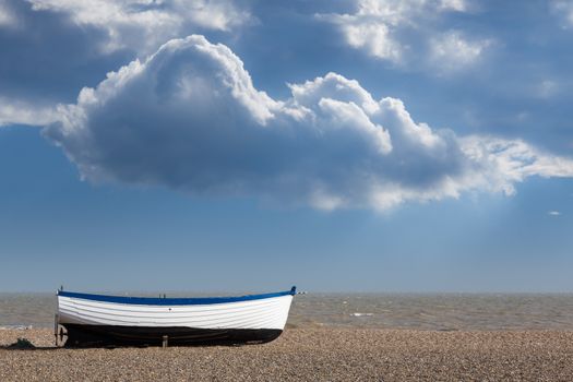 Ancient wooden painted fishing boat on pebble beach by North Sea in Aldeburgh Suffolk on East coast of England