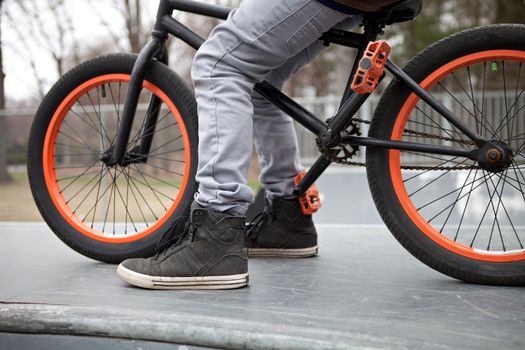 BMX bike rider parked atop a ramp at the skate park.