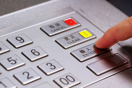 Hand entering personal identification number on ATM dial panel