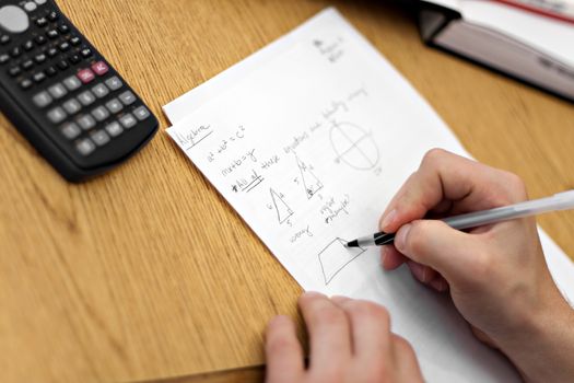 A young man working out mathematical equations on paper.