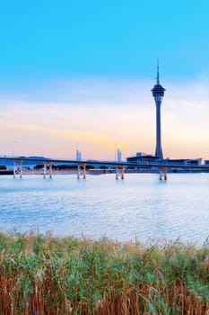 Urban landscape of Macau with famous traveling tower under blue sky near river in Macao, Asia. 