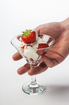 Strawberries with whipped cream and mint leaf in a glass on a white background