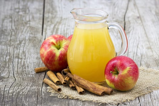 Apple juice and apples on wooden background