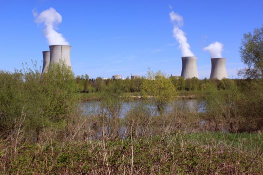 photo of an operating nuclear power plant on the banks of a river surrounded by trees