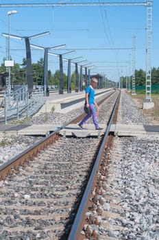 Man in blue walking across the railroad tracks