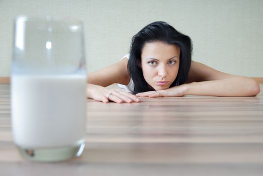 Photo of the glass with milk and woman laying on a parquet floor 