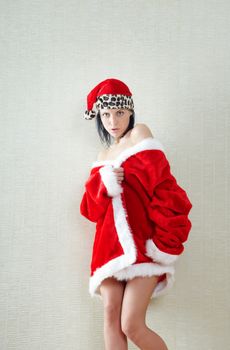 Smiling brunette lady indoors in the red furry Santa Claus dress and hat