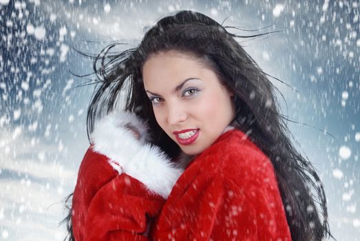 Sexy woman outdoors in the red coat of Santa Claus with snow fall