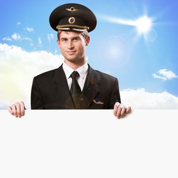 pilot in the form of holding an empty billboard on the background of sky with clouds, place for text