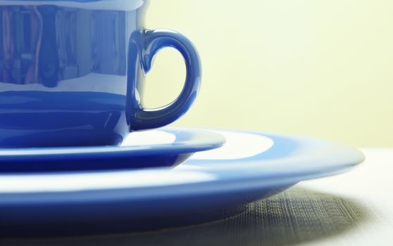 Blue teacup and plate on the table. Close-up photo with shallow depth of field for natural view