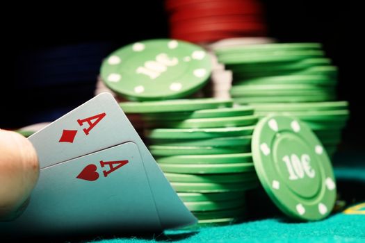 Pair of aces and poker chips on a green table in casino