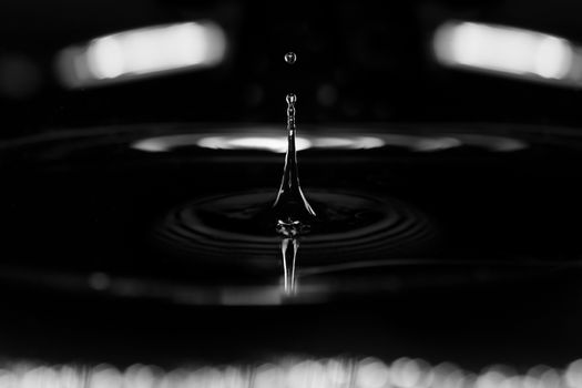 Extremely macro photo of the liquid splashing on a black background with light reflections