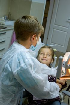 A couple of kids playing doctor at the dentist