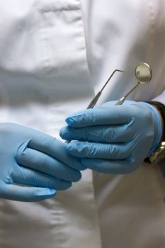 dentists hands in blue medical gloves with dental tools