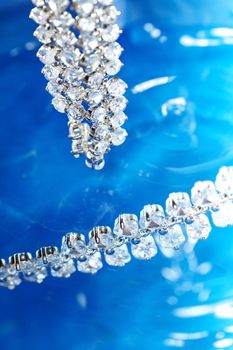 Close-up photo of the silver necklace with diamonds on a blue background with bokeh