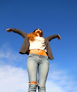 A young woman standing under a blue sky.