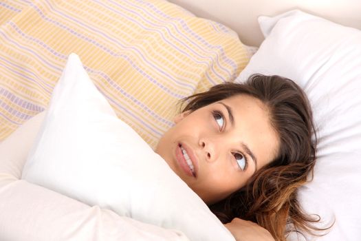 A daydreaming woman holding a pillow.