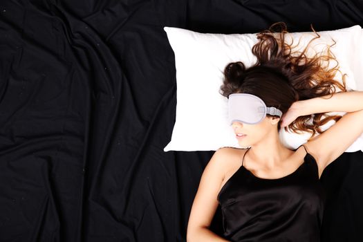 A young woman sleeping with a eye covering mask.