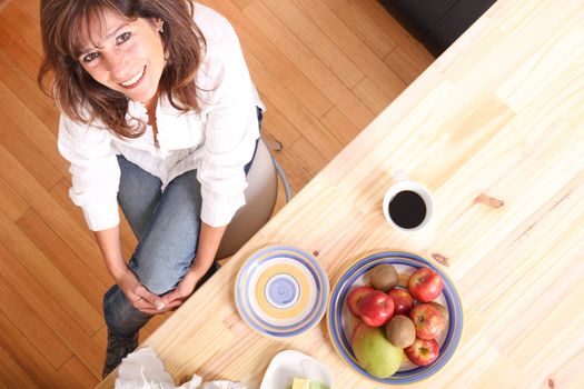 Portrait of a beautiful mature woman sitting in the kitchen. 