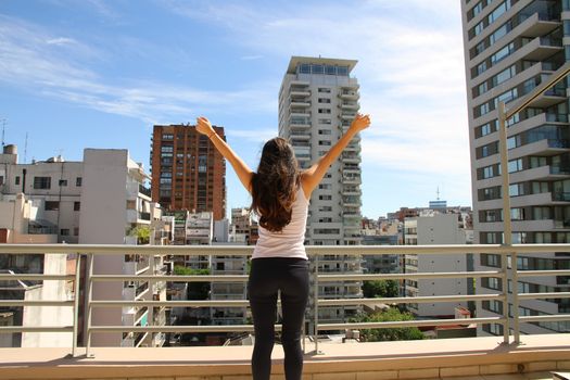 A young adult woman practicing Yoga in an urban environment.