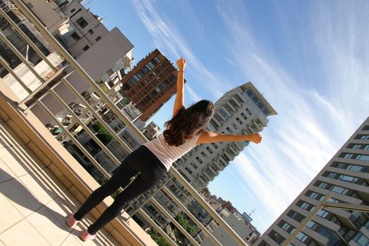 A young adult woman practicing Yoga in an urban environment.