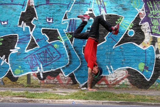 A performing HipHop Dancer in front of a Graffiti wall.