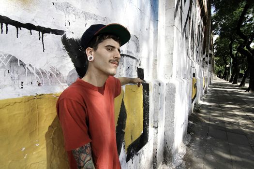A young Rapper leaning against a wall.