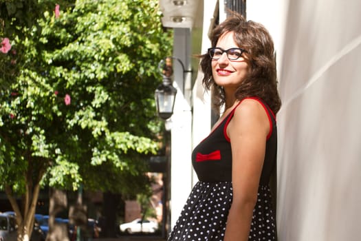 A vintage style dressed girl leaning at a wall and waiting.