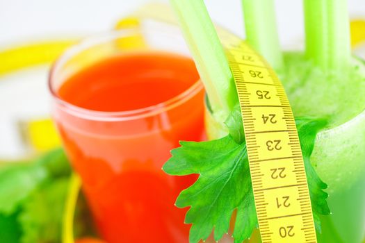 measuring tape, glass of celery juice and glass of carrot juice isolated on white