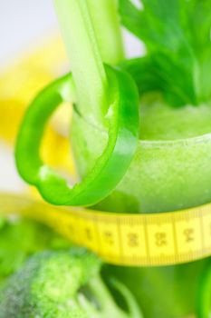 measuring tape,broccoli,pepper,celery and glass with celery juice 