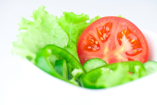 lettuce, tomato, cucumber and pepper in a bowl isolated on white