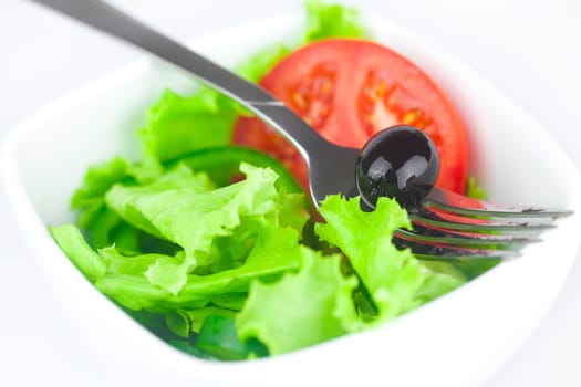 fork,black olive,lettuce, tomato, cucumber and pepper in a bowl