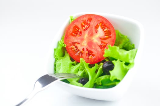 fork,lettuce, tomato, cucumber and pepper in a bowl isolated on white