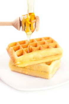 Belgian waffles on a plate, stick for honey and honey isolated on white