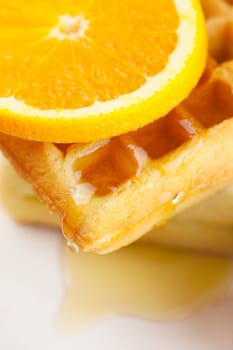 Belgian waffles,honey and orange on a plate isolated on white