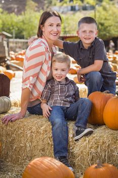 Attractive Mother and Her Two Sons Pose for a Portrait in a Rustic Ranch Setting at the Pumpkin Patch.
