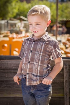 Adorable Little Boy at Pumpkin Patch With Hands in His Pockets Leaning on Antique Wood Wagon in Rustic Ranch Setting.
