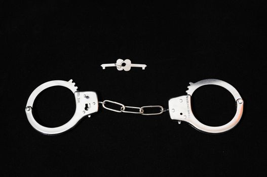 One Pair of Handcuffs on a Black Background