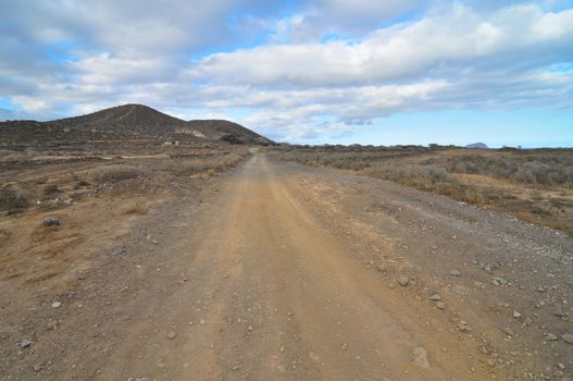 Sand and Rocks Road in the Desert on a Cloudy Sky